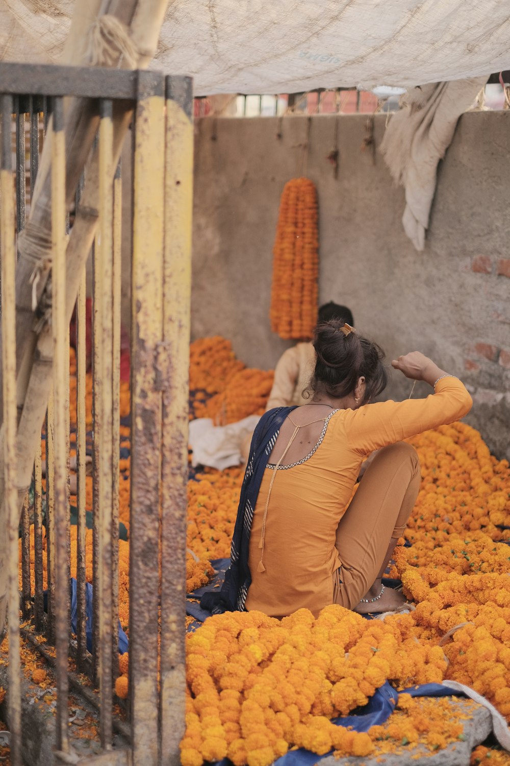 オレンジ色の花に囲まれた地面に座っている女性