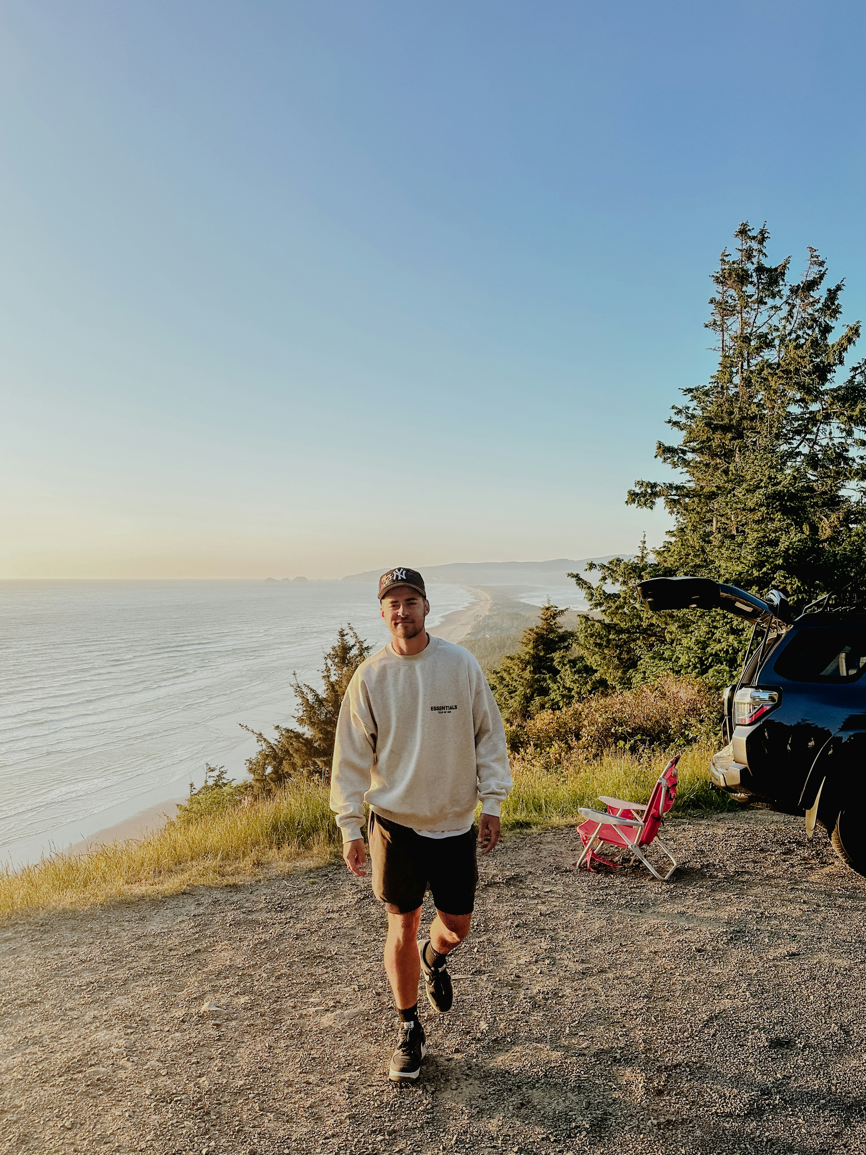 a man standing on top of a hill next to a car
