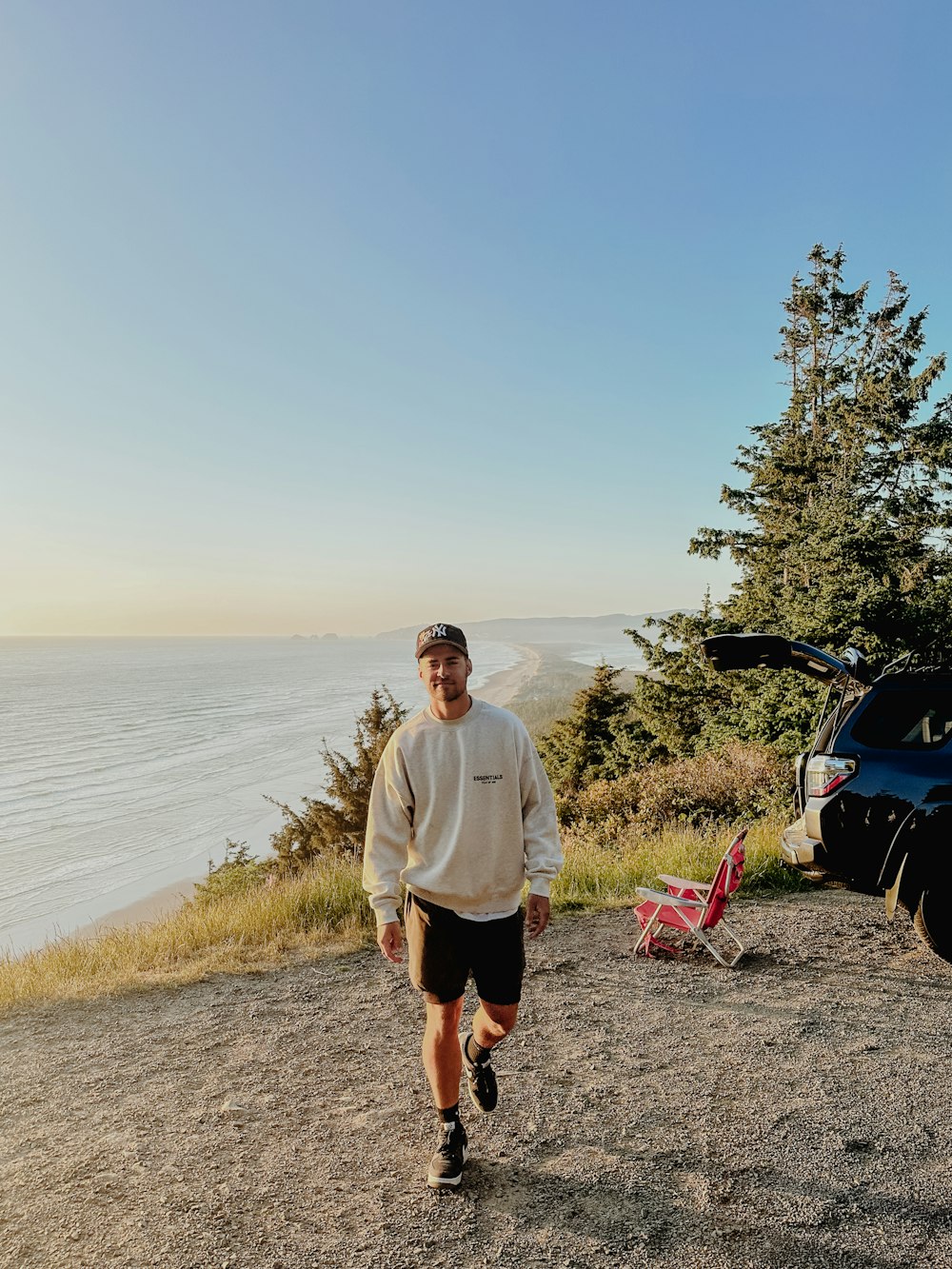 a man standing on top of a hill next to a car