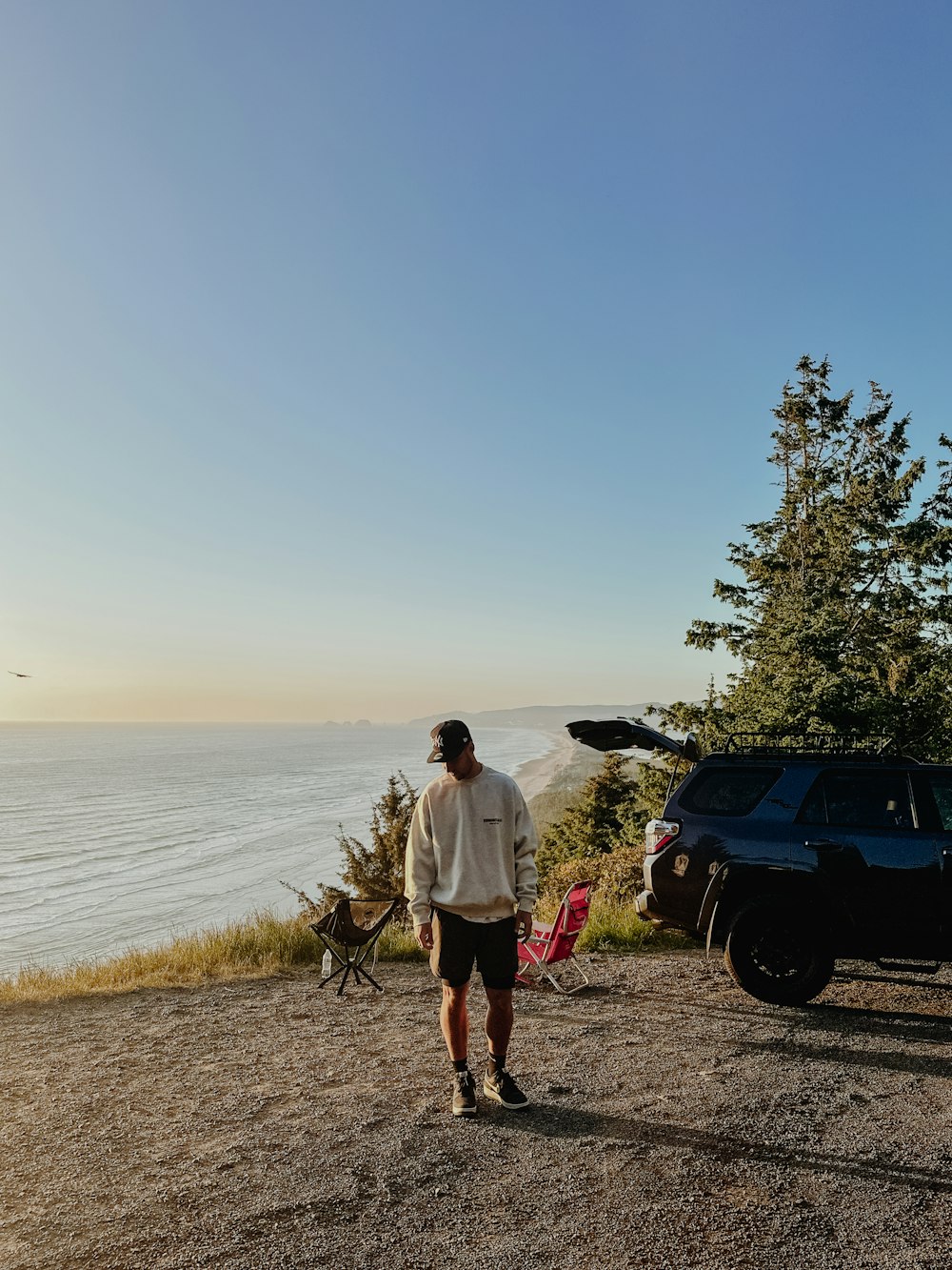 a man walking on a dirt road next to a car