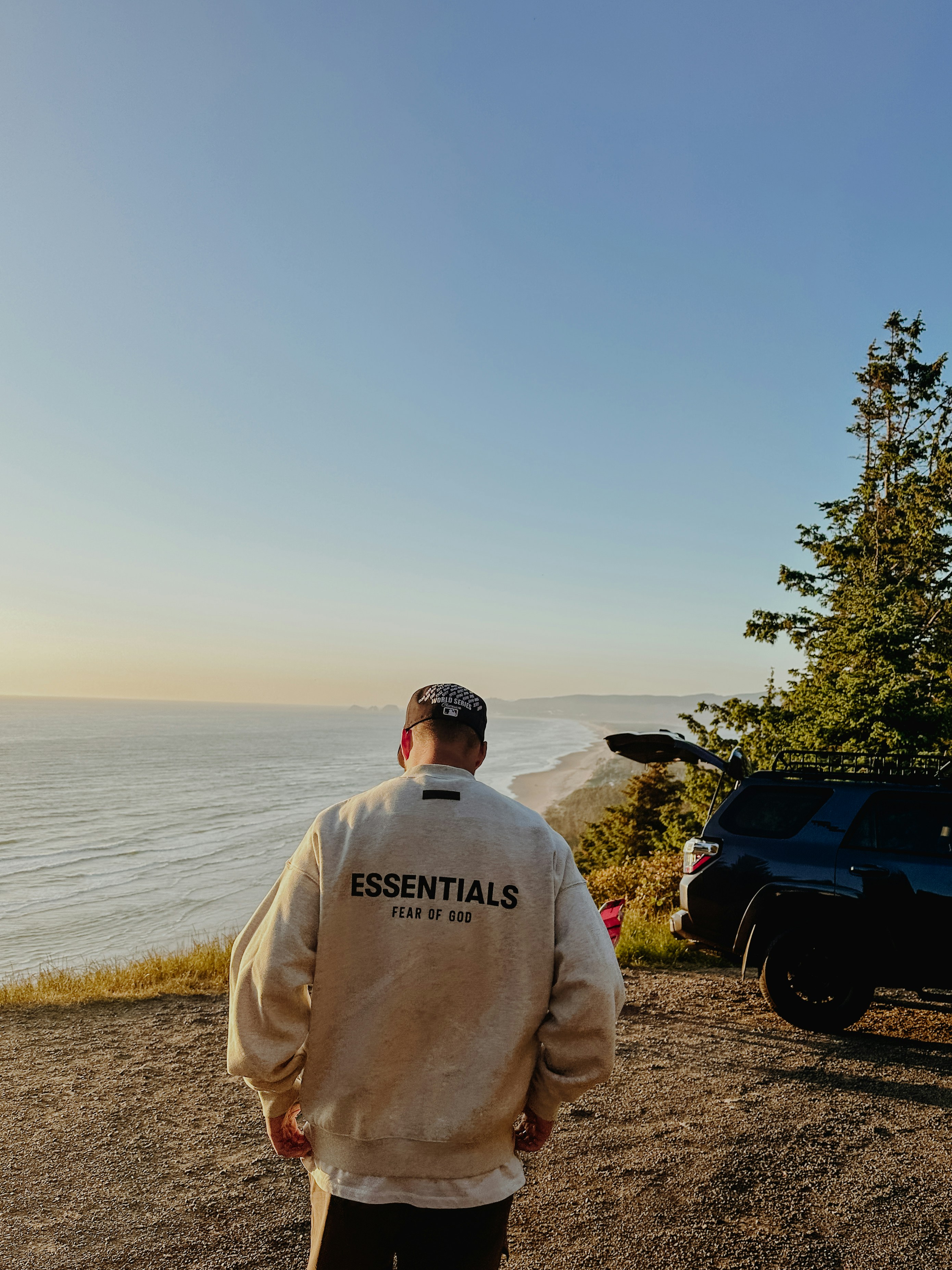 a man standing on top of a hill next to the ocean