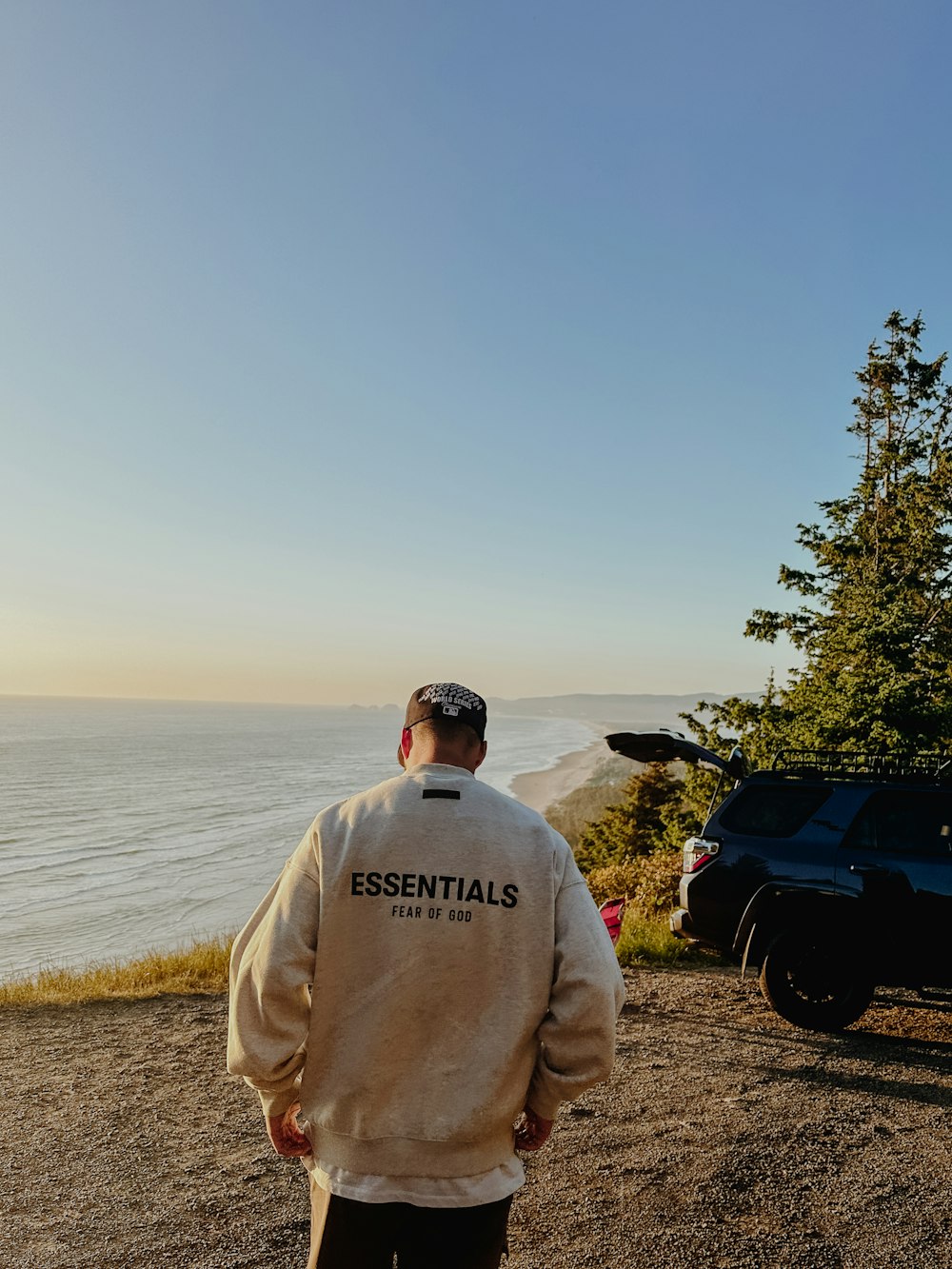 a man standing on top of a hill next to the ocean