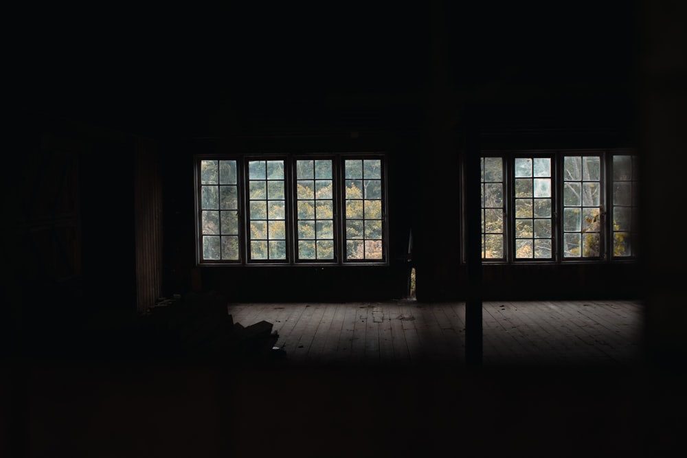 a dark room with two windows and a person sitting on the floor