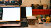 Creative workspace with design tools, coffee cup, and Android figurines on a wooden desk.