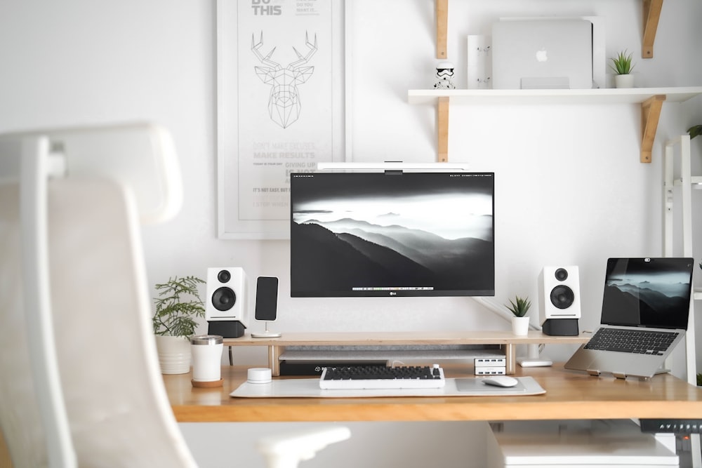 a desk with a laptop, monitor, keyboard and speakers