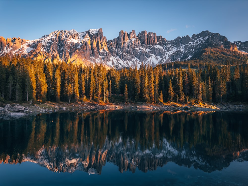 a mountain range is reflected in the still water of a lake