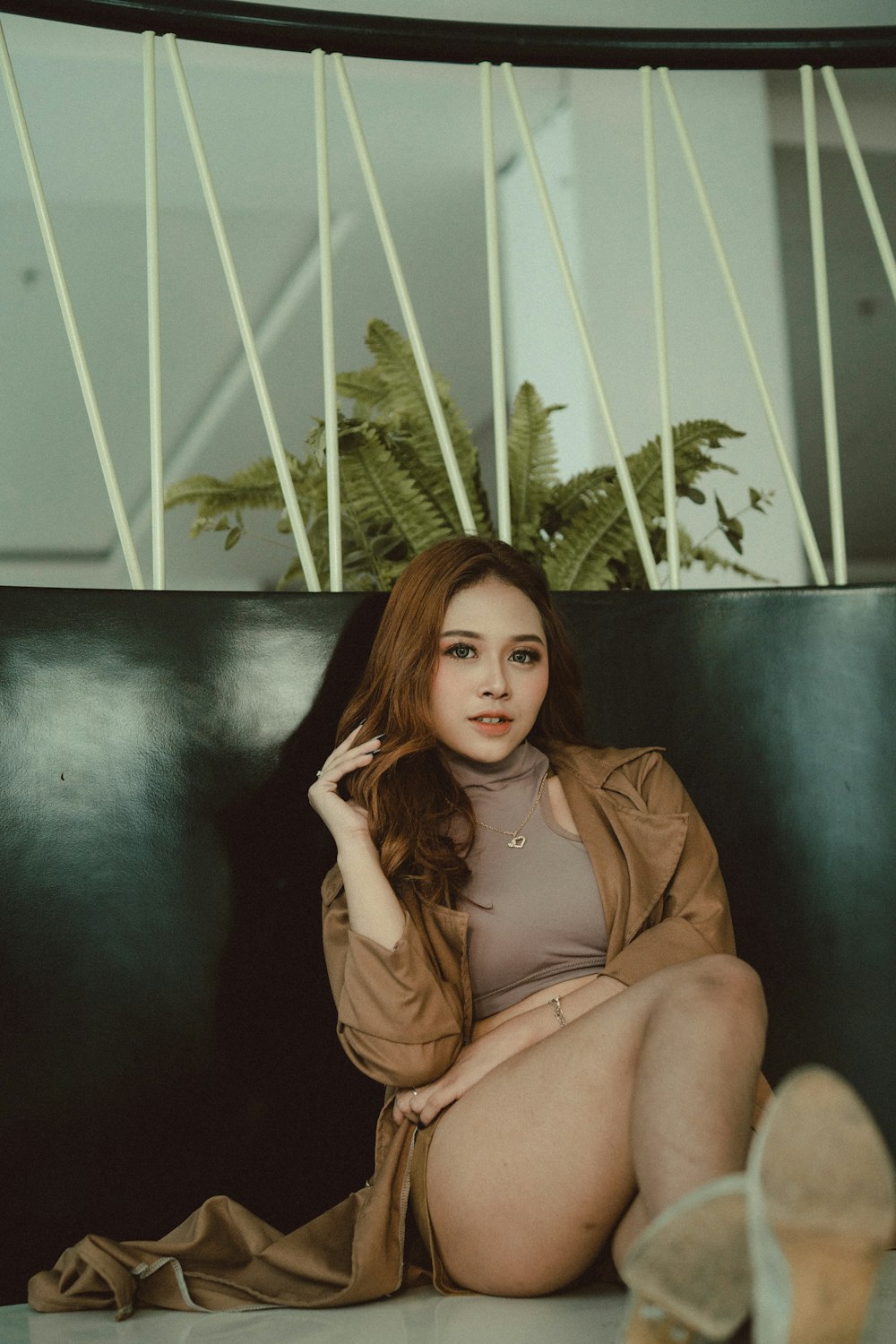 a woman sitting on top of a couch next to a plant