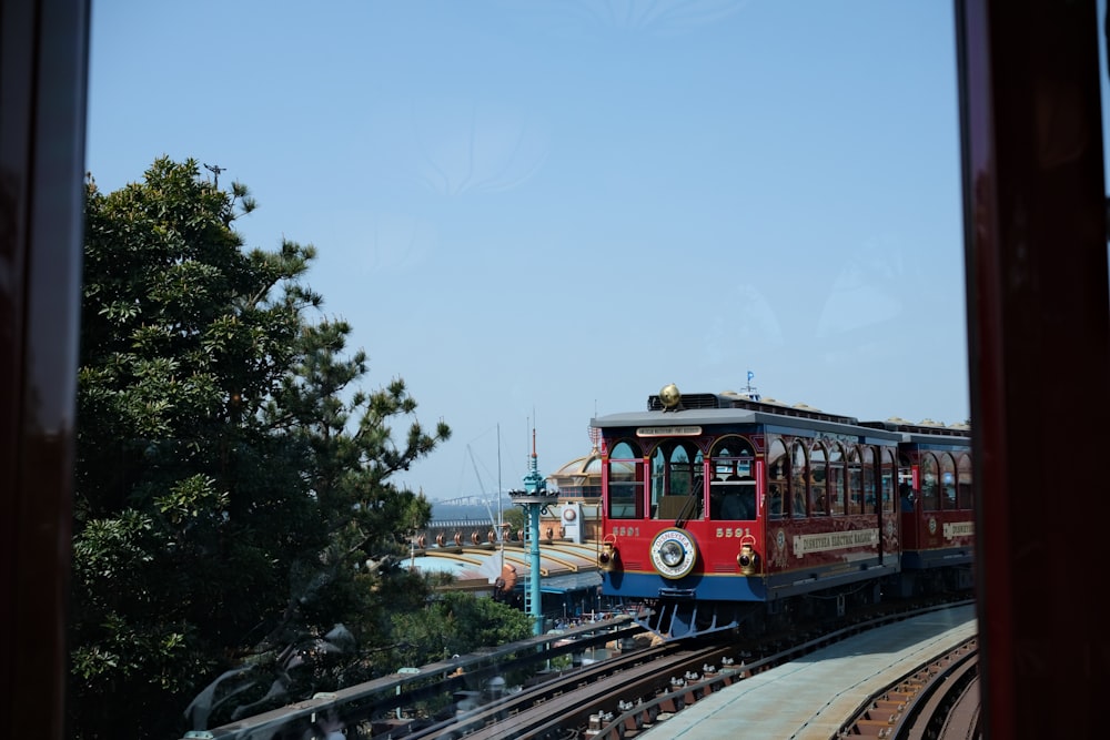 a red train traveling down train tracks next to a forest