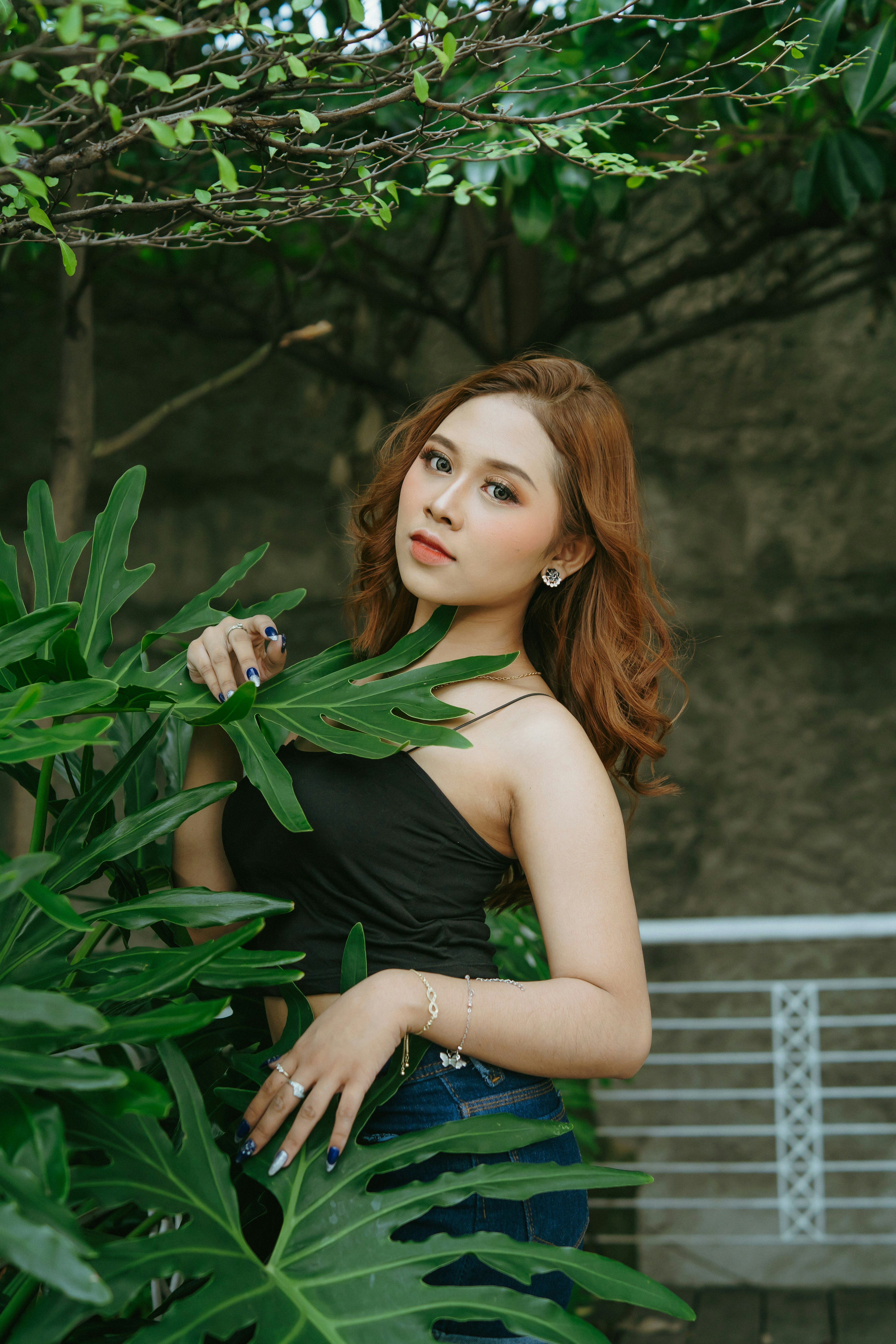 a beautiful young woman standing next to a tree