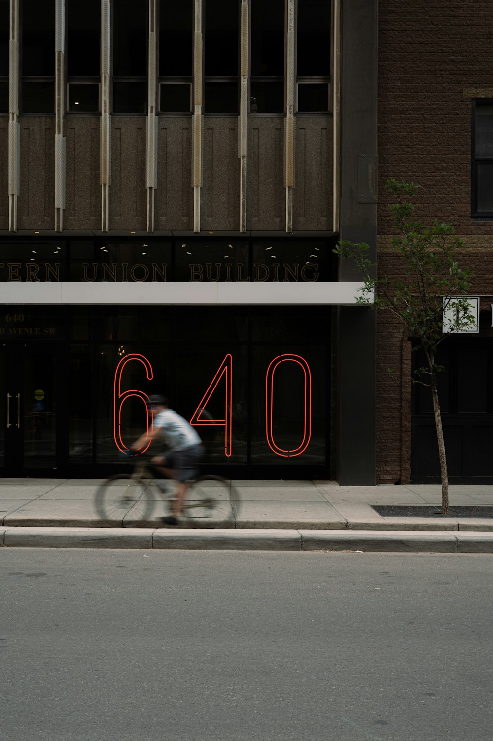 a man riding a bike down a street next to a tall building