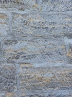 Before and after photos of a stone wall restoration in a residential home.