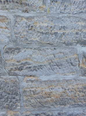 Before and after photos of a stone wall restoration in a residential home.