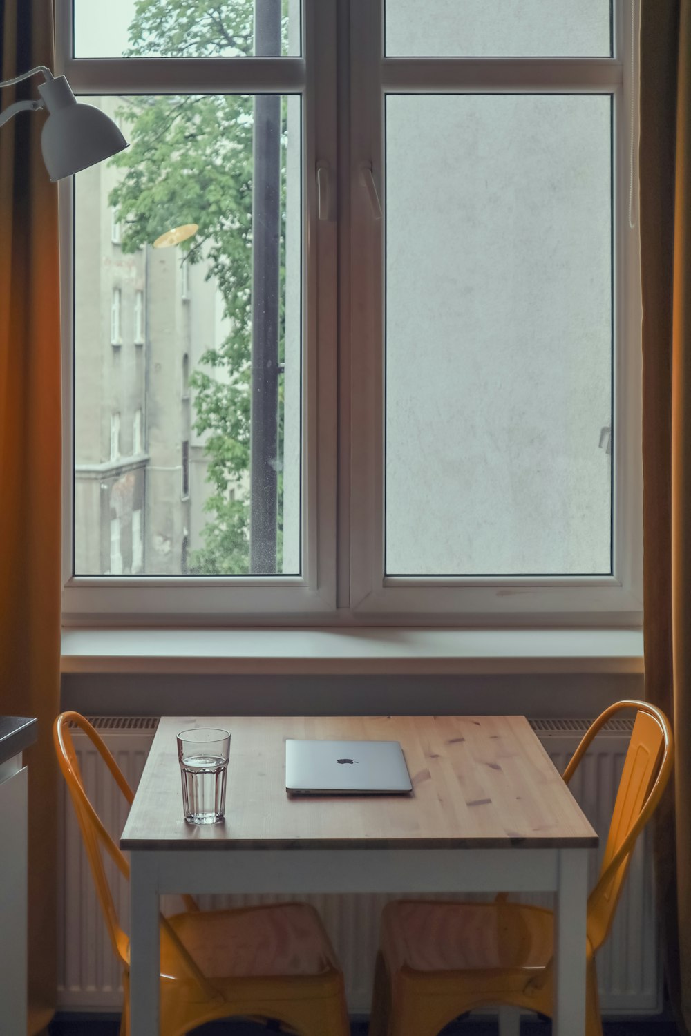a table with a laptop on it in front of a window