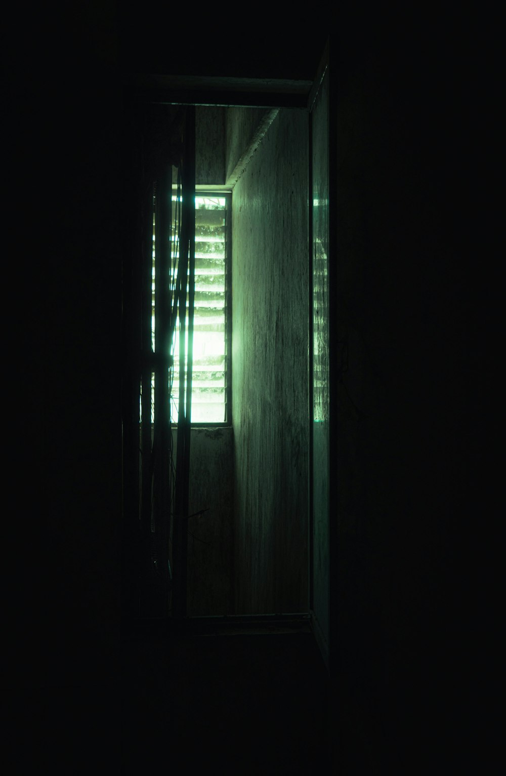a dark room with a window and blinds in it
