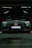 Elegant black luxury car parked in a pristine garage with golden accents.