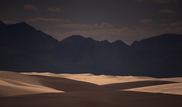 A cinematic frame from a music video featuring vibrant shadows cast on a desert landscape at dusk.