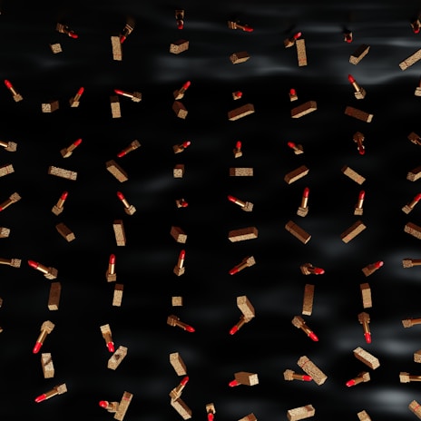 Classic red press-on nails shown with a matching lipstick and gold rings.