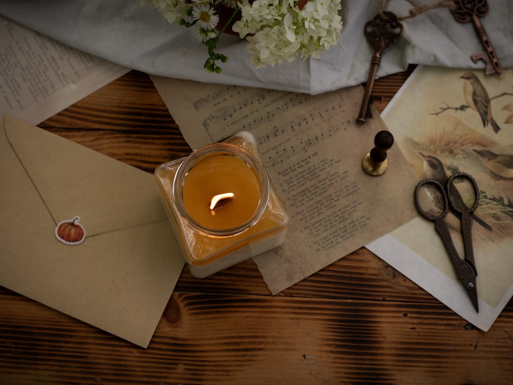 a candle sits on a table next to a pair of scissors