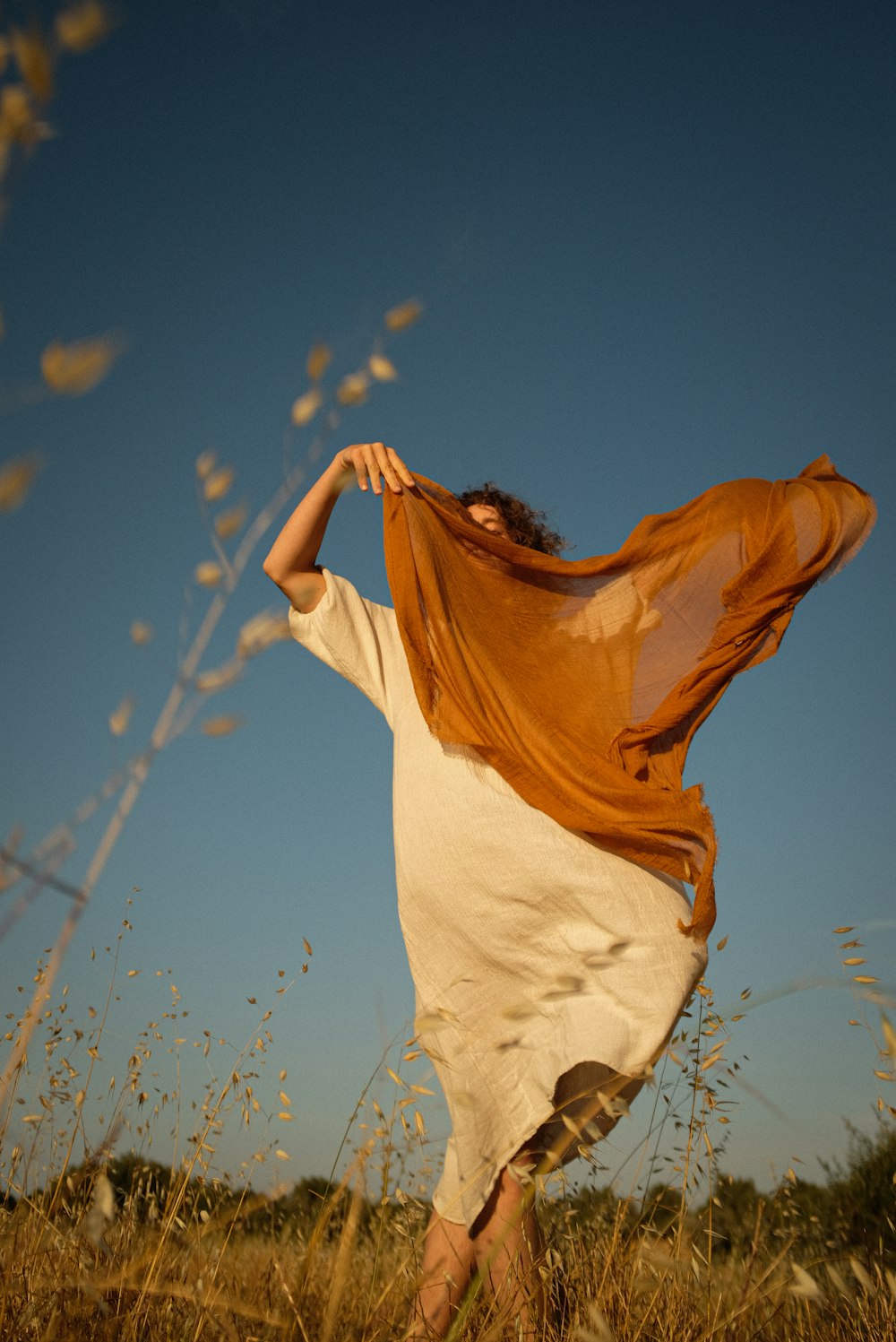 a woman standing in a field with a scarf around her neck