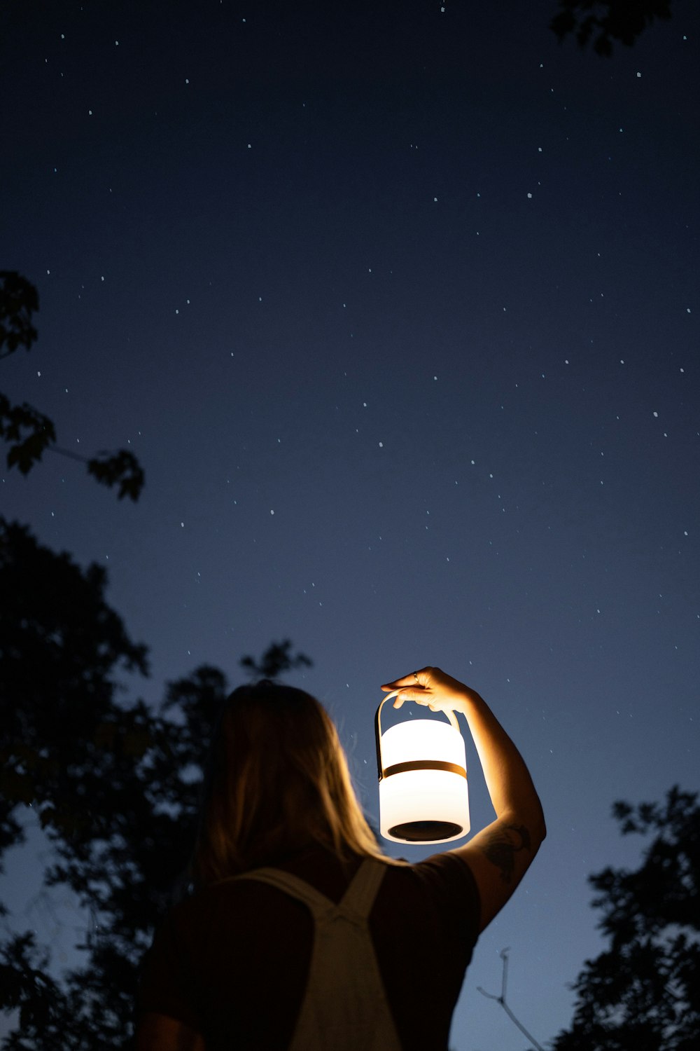 a woman is holding a lantern in the dark