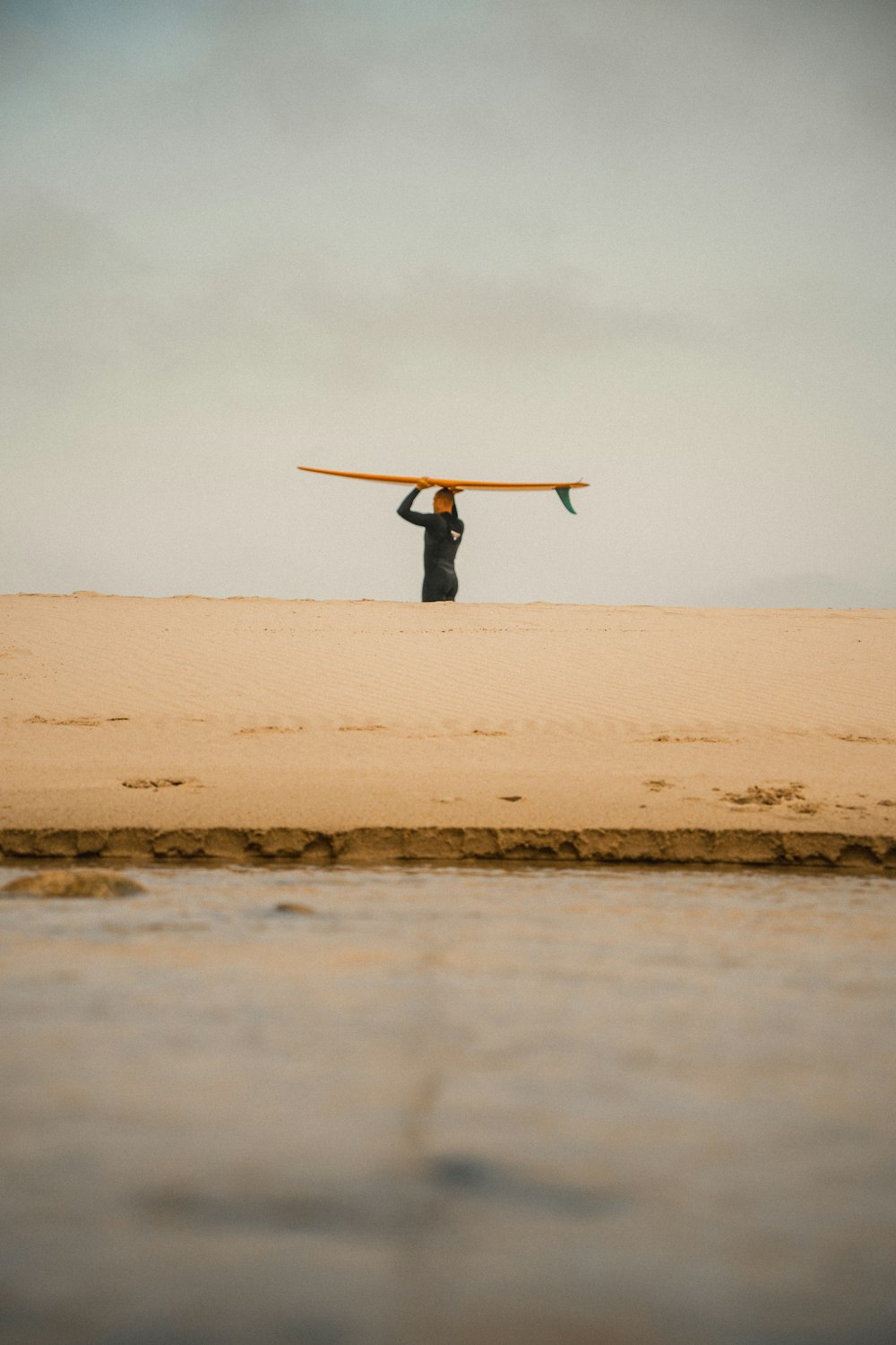 a man holding a surfboard over his head on the beach