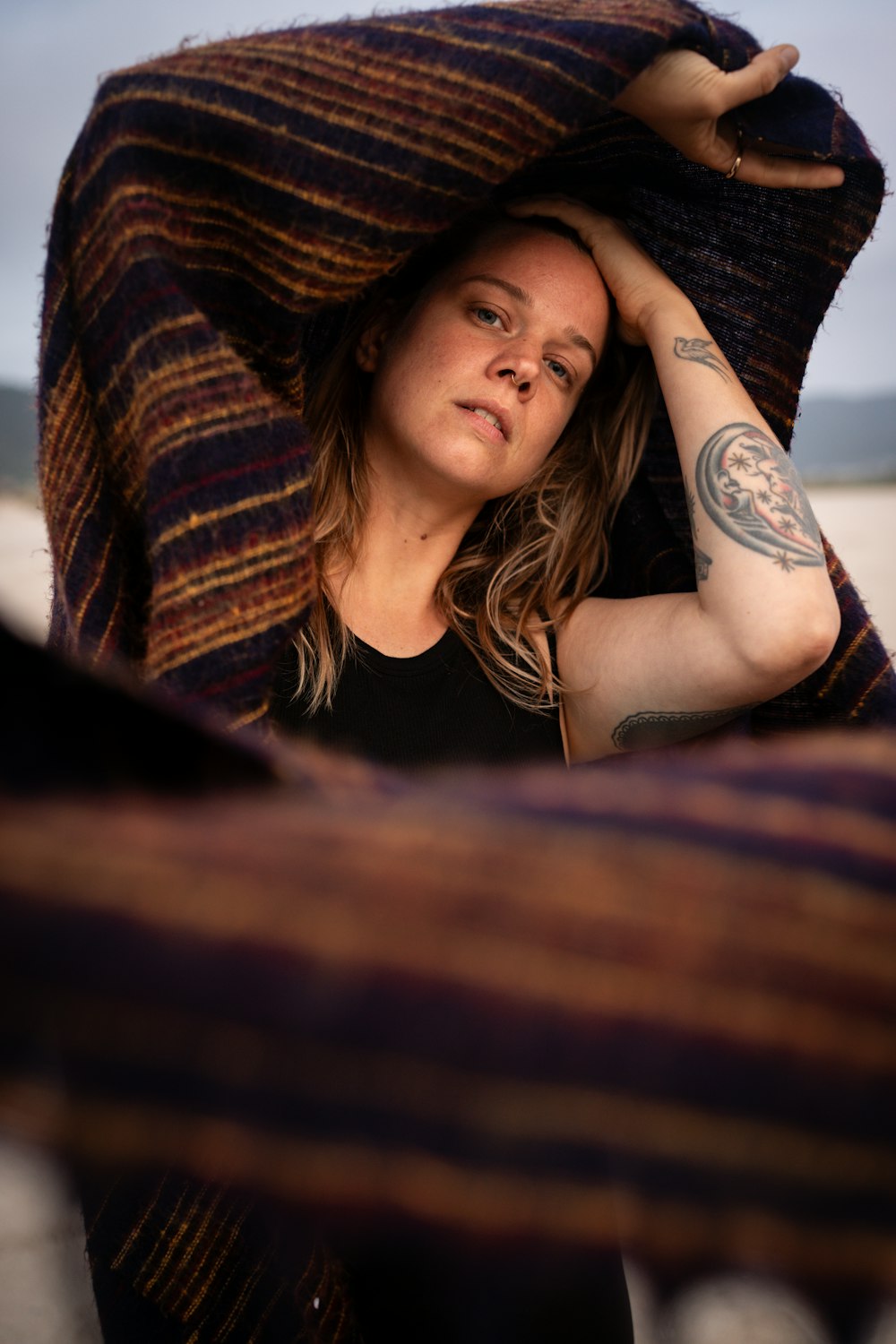 a woman wrapped in a blanket on the beach