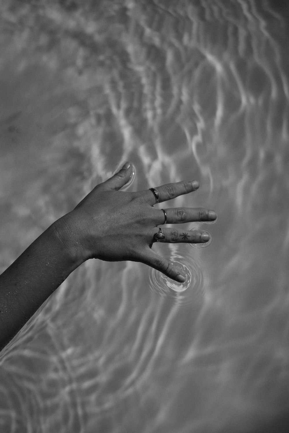 a person's hand reaching for a frisbee in the water