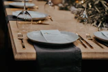 Elegant golden menu holder displayed on a rustic wooden restaurant table with a softly lit background.