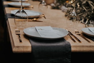 An elegant restaurant menu laid out on a table with cutlery and a glass of wine.