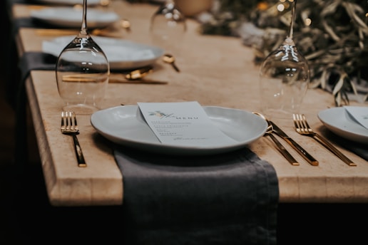 An elegant restaurant menu laid out on a table with cutlery and a glass of wine.