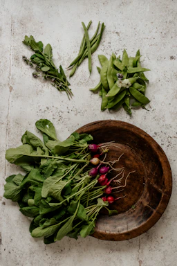 Close-up of vibrant, freshly picked vegetables arranged in a rustic wooden crate on a farm table.
