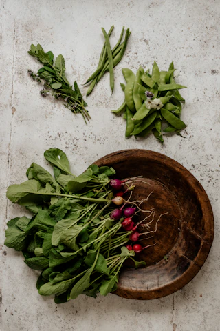 Close-up of colorful fruits and leafy greens arranged artistically on a rustic surface.
