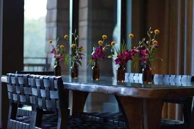 Dining space with simple wooden tables and fresh local flowers as centerpiece.
