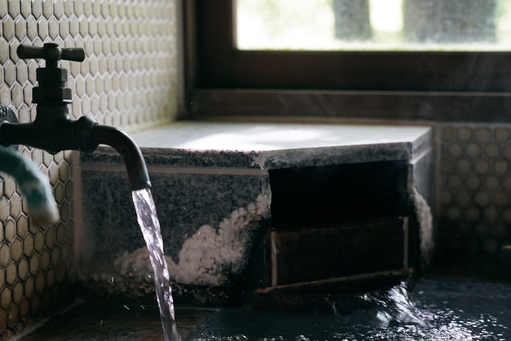 a faucet with water running out of it next to a window