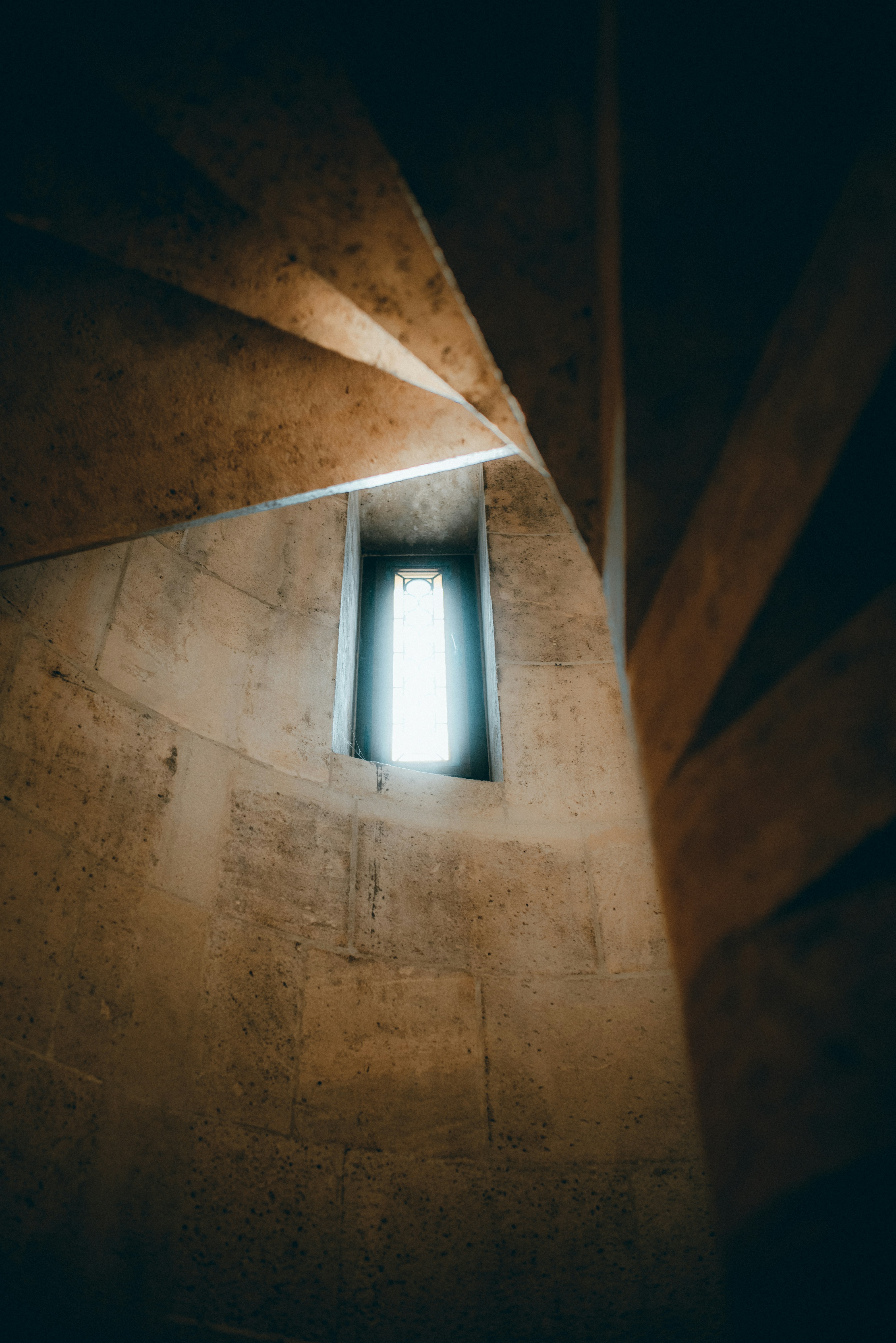a window in a stone wall with a light coming through it