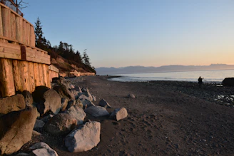 Engineers inspecting a seawall structure along a rugged coastline at sunset.