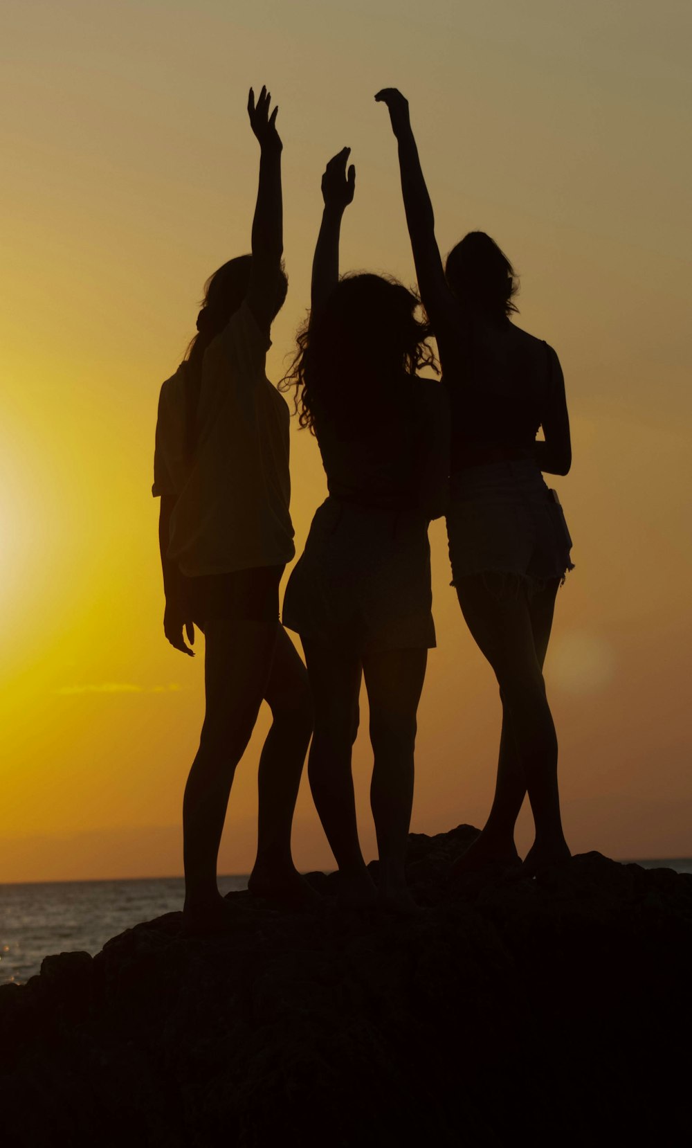 a group of people standing on top of a beach next to the ocean