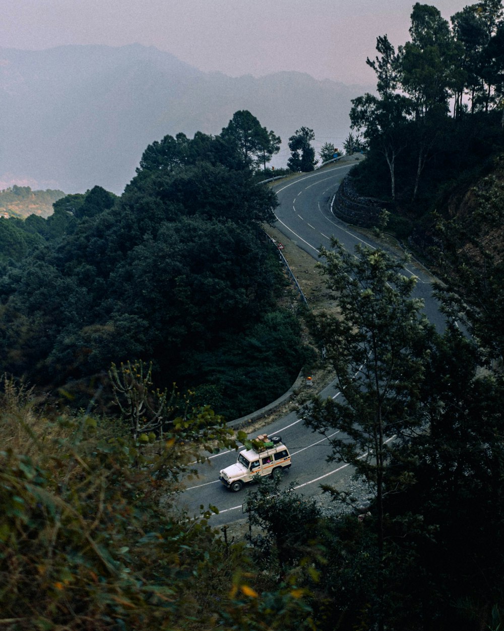 a bus driving down a road surrounded by trees