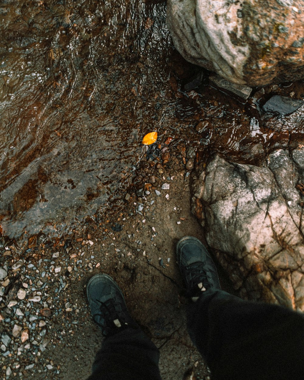 a person standing next to a large rock