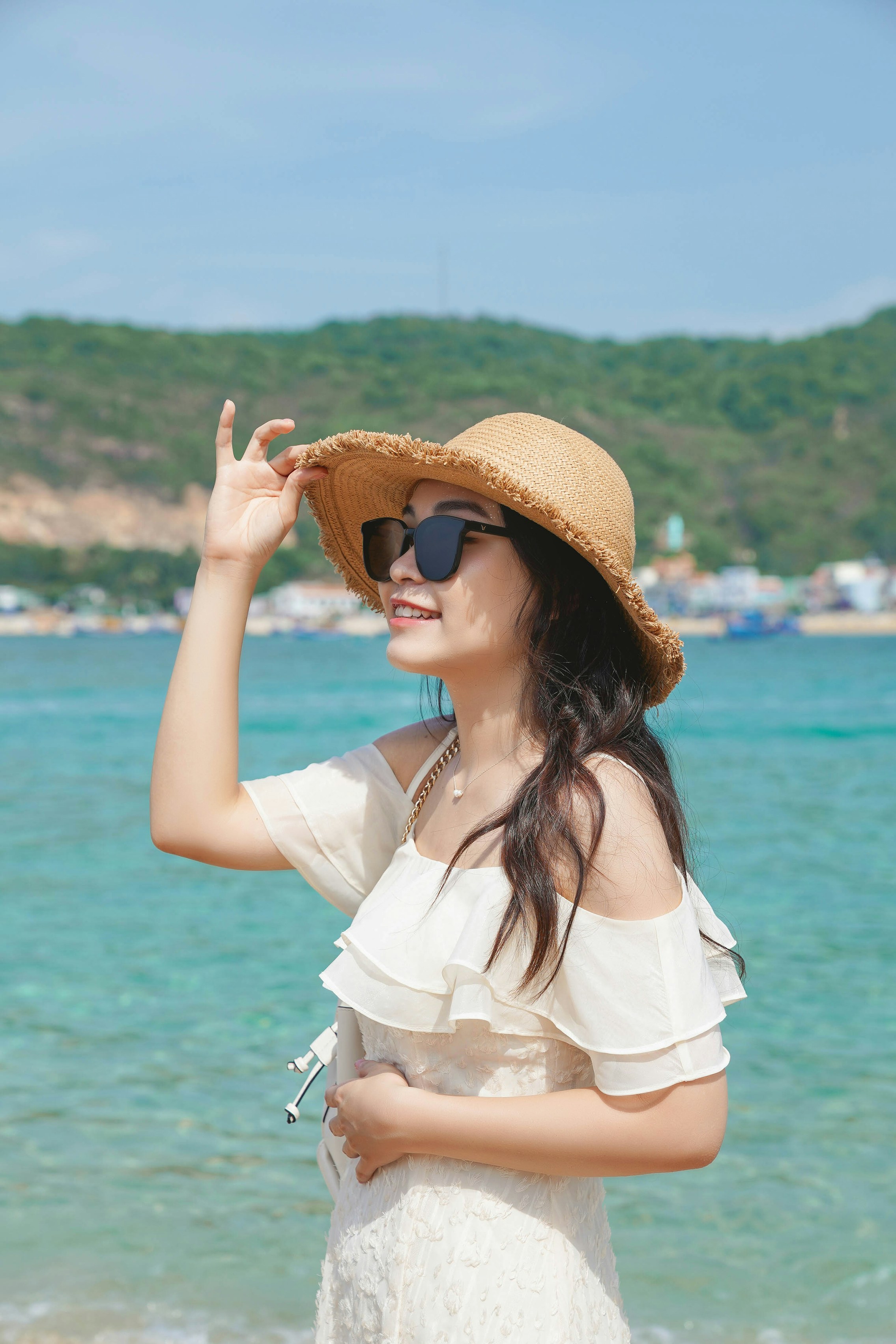 A woman standing on a beach wearing a hat and sunglasses photo – Free ...