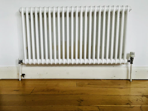 Close-up of a sleek black soapstone radiator with subtle white veins, set against a minimalist white wall.
