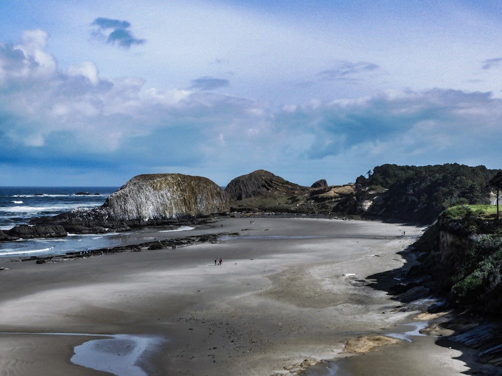 a sandy beach next to the ocean under a cloudy sky