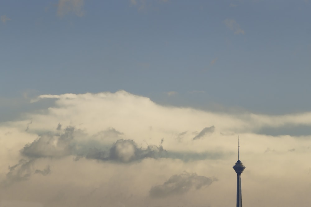 a tall tower in the middle of a cloudy sky