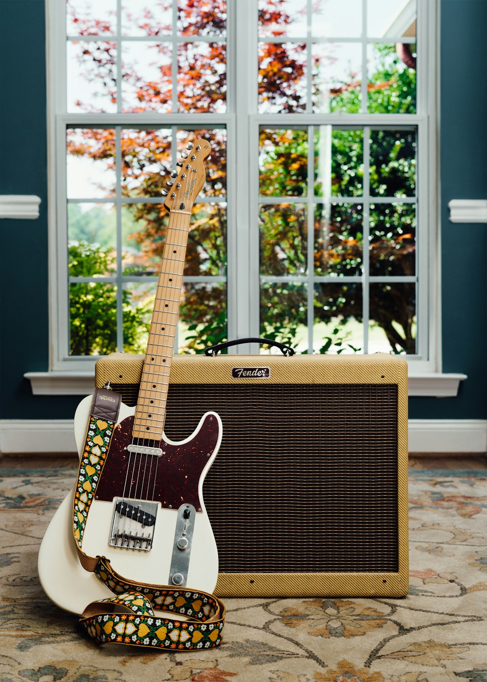 a guitar and amp sitting in front of a window