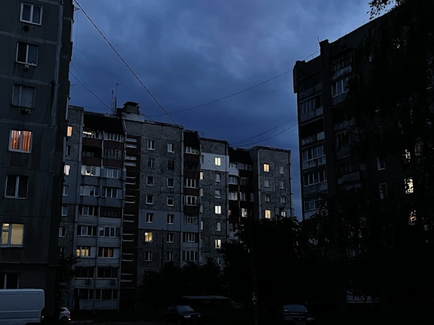 Dark overlay image of Neuquén cityscape at dusk with modern buildings and calm streets.