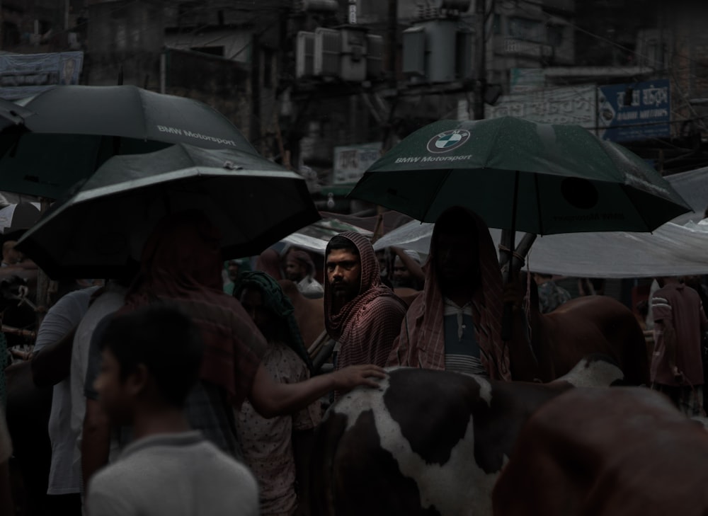 a group of people standing around with umbrellas