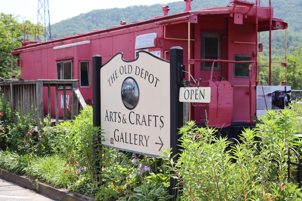 a red train car sitting next to a lush green field