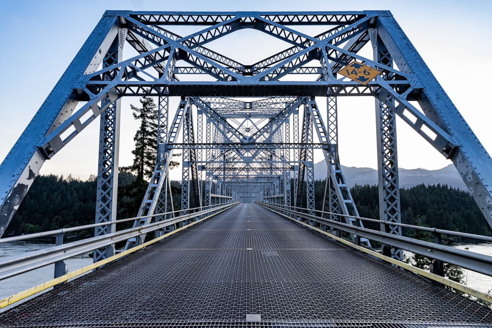 a blue metal bridge with a sign on it