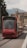 A red tram labeled 'Wabern' travels along a city street with historic architecture and faint hills visible in the background. The tram displays a message indicating it is CO2 neutral, emphasizing its environmental friendliness.