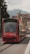 A red tram labeled 'Wabern' travels along a city street with historic architecture and faint hills visible in the background. The tram displays a message indicating it is CO2 neutral, emphasizing its environmental friendliness.